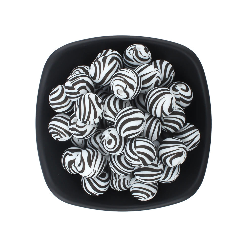 A black bowl filled with white and black striped silicone beads for jewelry making.