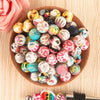 A bowl filled with colorful, round silicone beads for jewelry making in various shades of pink, yellow, blue, and black.