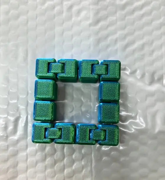 A square puzzle made of interlocking green fidget cubes used for stress relief and focus.