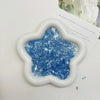 A white, flower-shaped mold filled with blue iridescent acrylic ice strips for nail art and crafts.