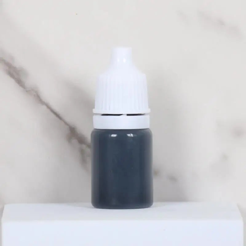 A small dark gray bottle with a white cap sits on a white surface.