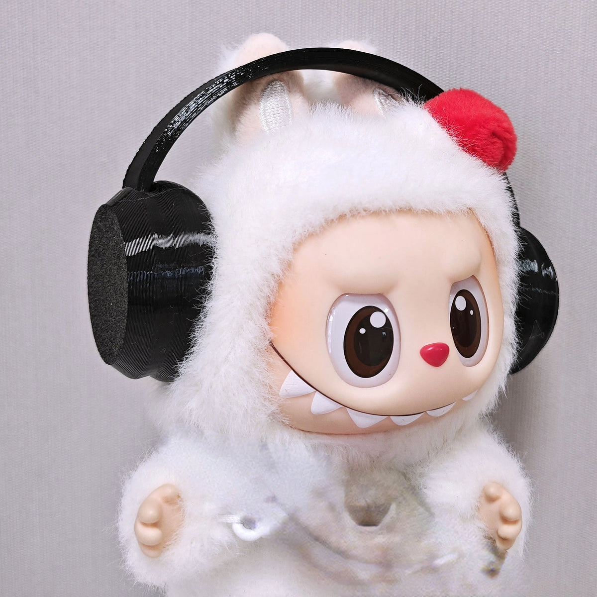 Labubu doll wearing a white bear hoodie and black headphones