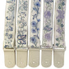 A set of light-colored woven guitar straps with floral embroidery and leather accents.