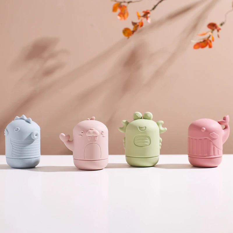 Four soft silicone animal bath toys in light blue, pink, green, and pink are displayed on a white surface.