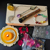 A witchcraft starter kit displayed on a wooden box featuring crystals, herbs, and an oil lamp.