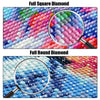 Close-up view of a diamond painting mosaic featuring various shades of blue and pink stones under a magnifying glass.