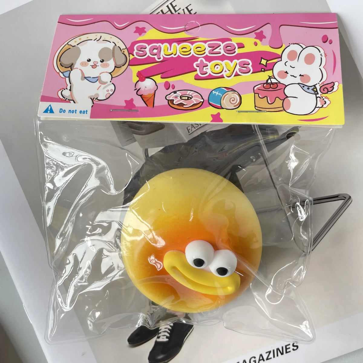 A yellow squishy toy shaped like a piece of bread with a face, packaged in clear plastic.