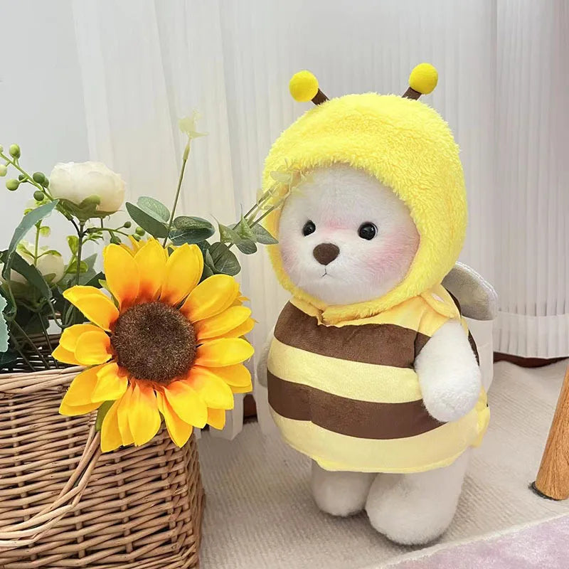 A yellow and brown striped plush doll wearing a yellow hood, standing next to a sunflower.