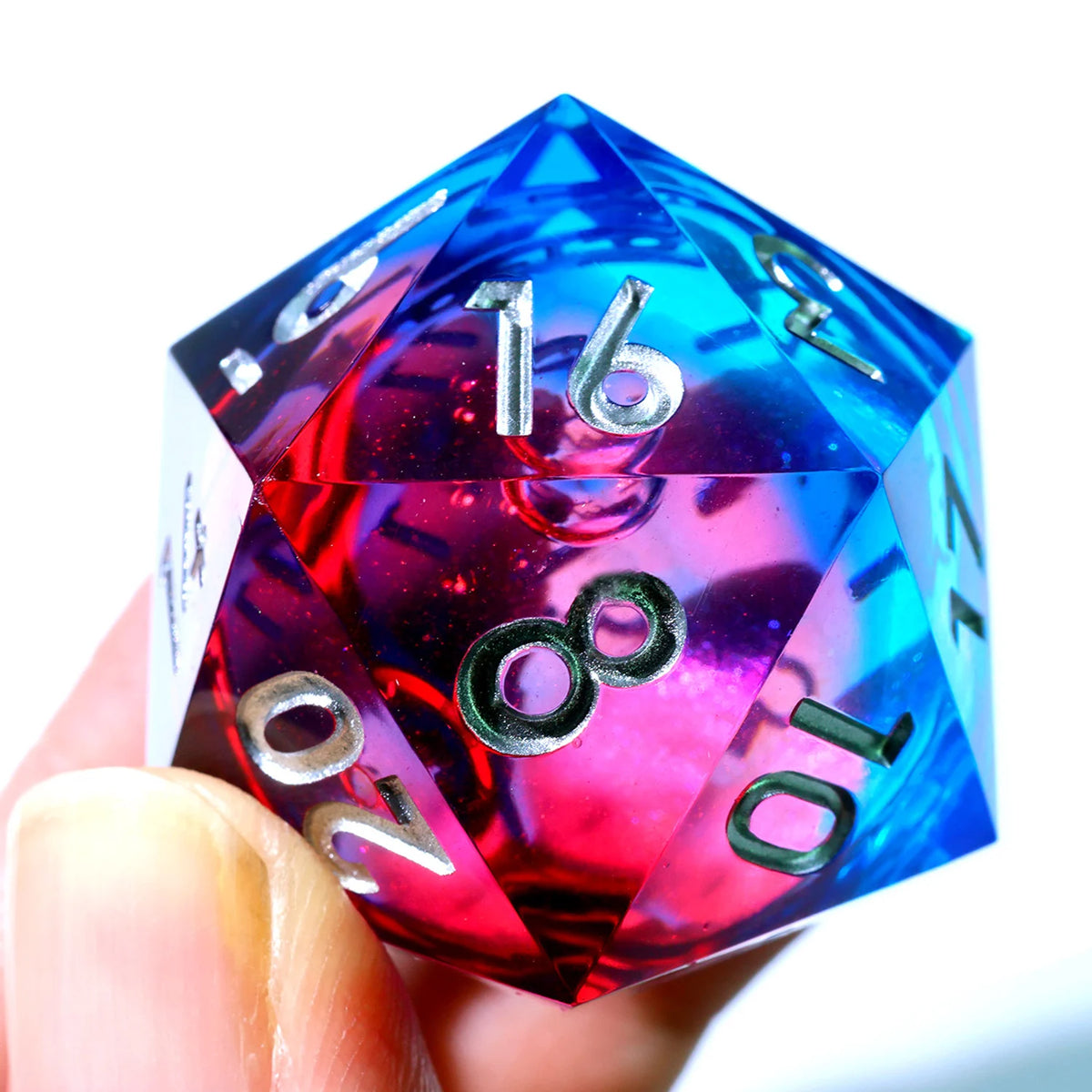 A hand holds a large blue and purple liquid swirl resin D20 die with a sharp geometric cut.
