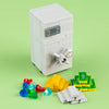 A white building block treasure chest set with gold and silver coins scattered on a green surface.