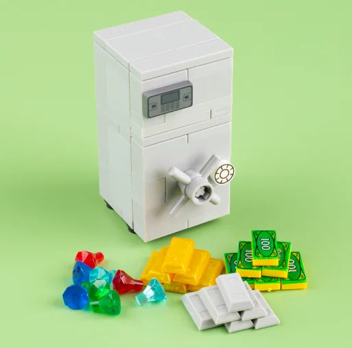 A white building block treasure chest set with gold and silver coins scattered on a green surface.