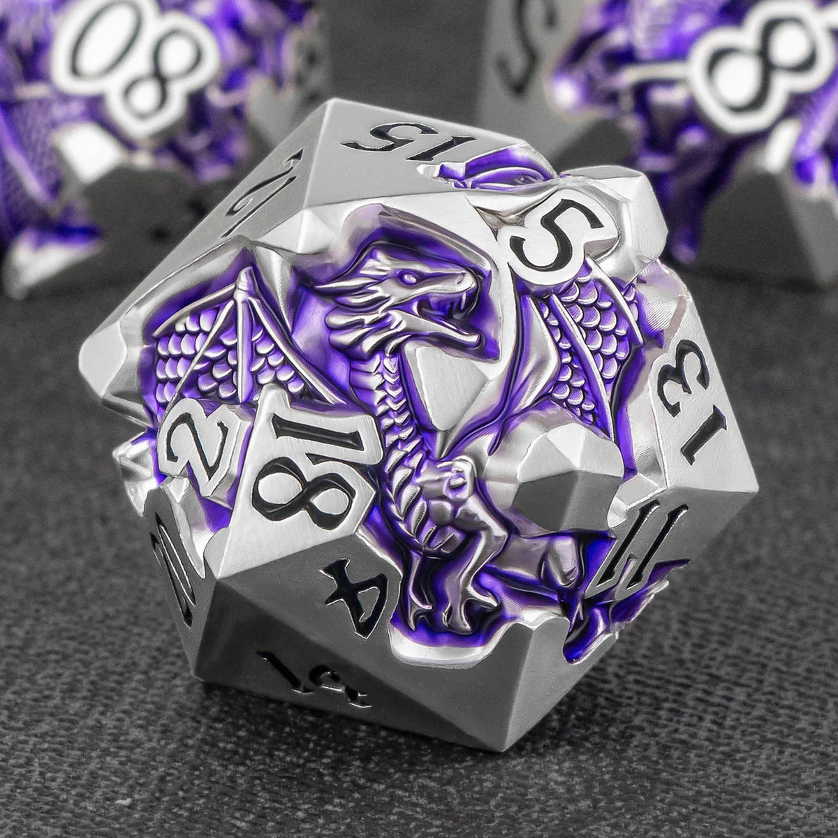 A silver metal die featuring a dragon design and numbered faces, set against a dark background.