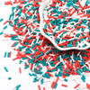 A pile of colorful polymer clay slice sprinkles in red, white, and teal scattered on a white surface with a small white dish.