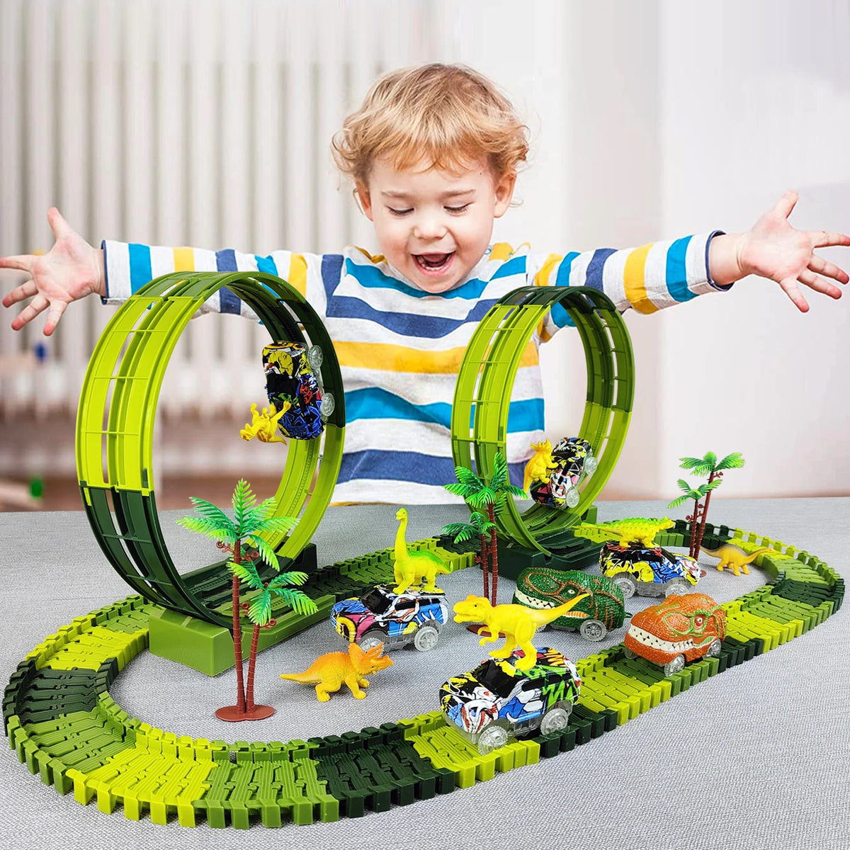 A child is holding a green dinosaur climbing car track set with various dinosaur figures on a green track.