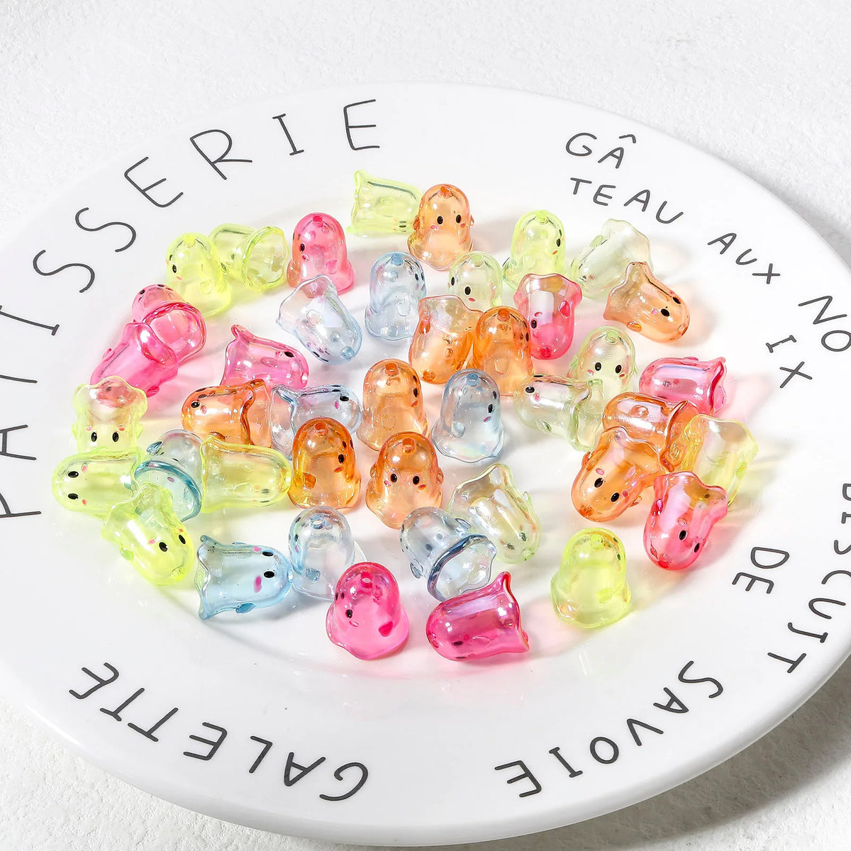 A collection of translucent acrylic ghost beads in various colors is displayed on a white plate.