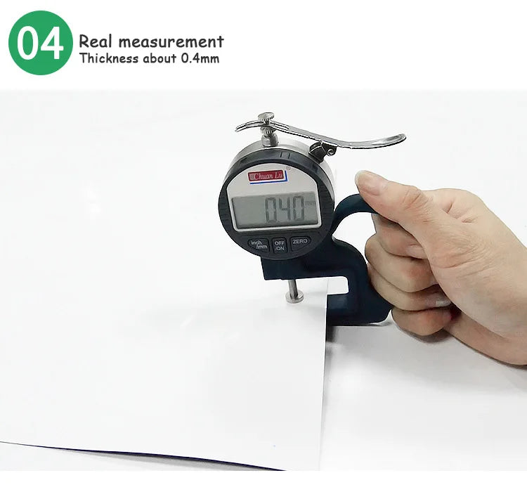 A hand is using a digital thickness gauge to measure the 0.4mm thickness of a flexible magnetic dry erase board.