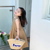 A young girl wearing a beige sleeveless cotton sundress stands outdoors near a white door.