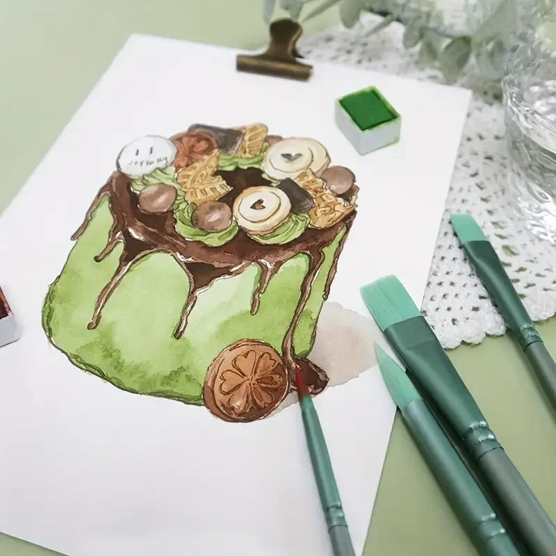 A watercolor painting of a green cake with chocolate frosting and leaves, surrounded by various paintbrushes.