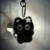 A black plush cat with large yellow eyes and a silver star charm hanging from a metal keyring.