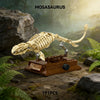 A detailed model of a Mosasaurus dinosaur skeleton built from brown plastic blocks displayed in a natural outdoor setting.