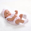A lifelike vinyl reborn doll with a pink outfit and matching hat lying on a white surface.