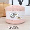 A ball of pink cotton yarn labeled as Cotton Yarn 100g, shown on a wooden surface.