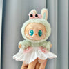 A cute doll wearing a light green fuzzy outfit and a white ruffled skirt with pink flowers.