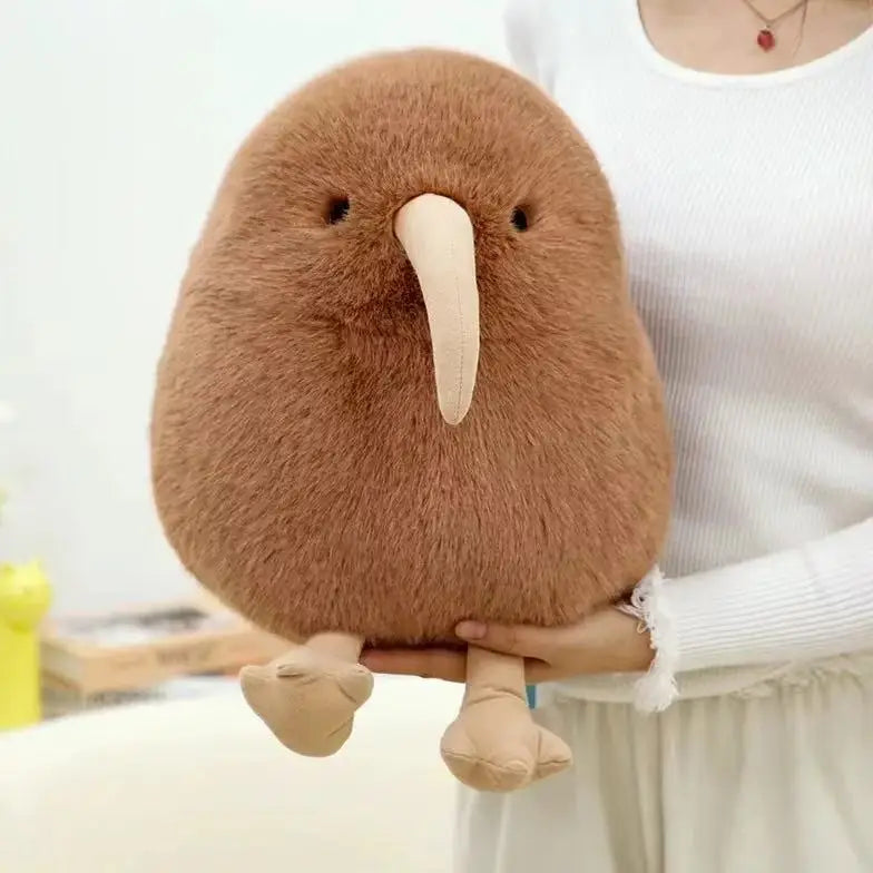 A brown kiwi bird plush toy with a long beak is being held by a person.