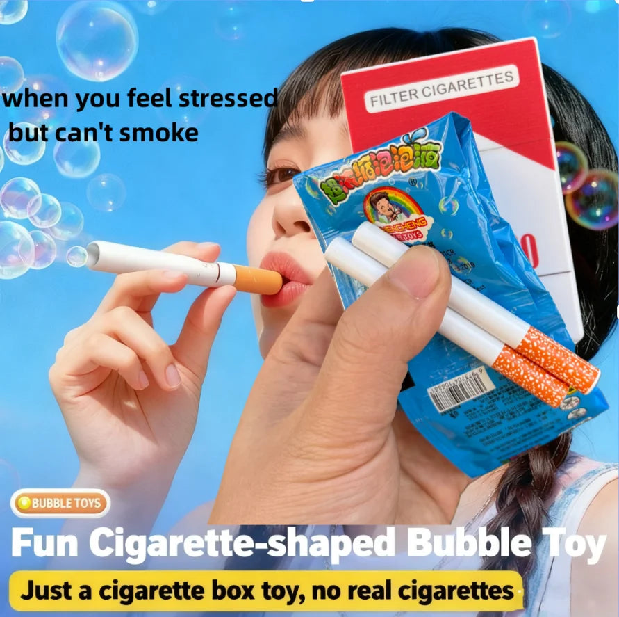 A hand is blowing a white cigarette-shaped bubble toy, next to a box of filter cigarettes.