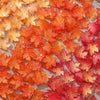 Orange and red maple leaf glass beads scattered on a mesh surface for DIY jewelry making