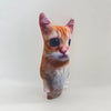 A plush doll of an orange tabby cat with large, dark eyes and pinkish fur.