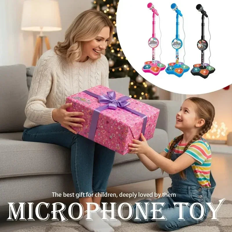A smiling woman gives a microphone toy to a young girl in a living room setting.