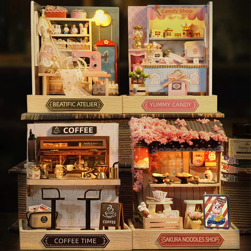 A display of various wooden miniature dollhouse kits including a Beatific Atelier, Yummy Candy, and Coffee Time shop.