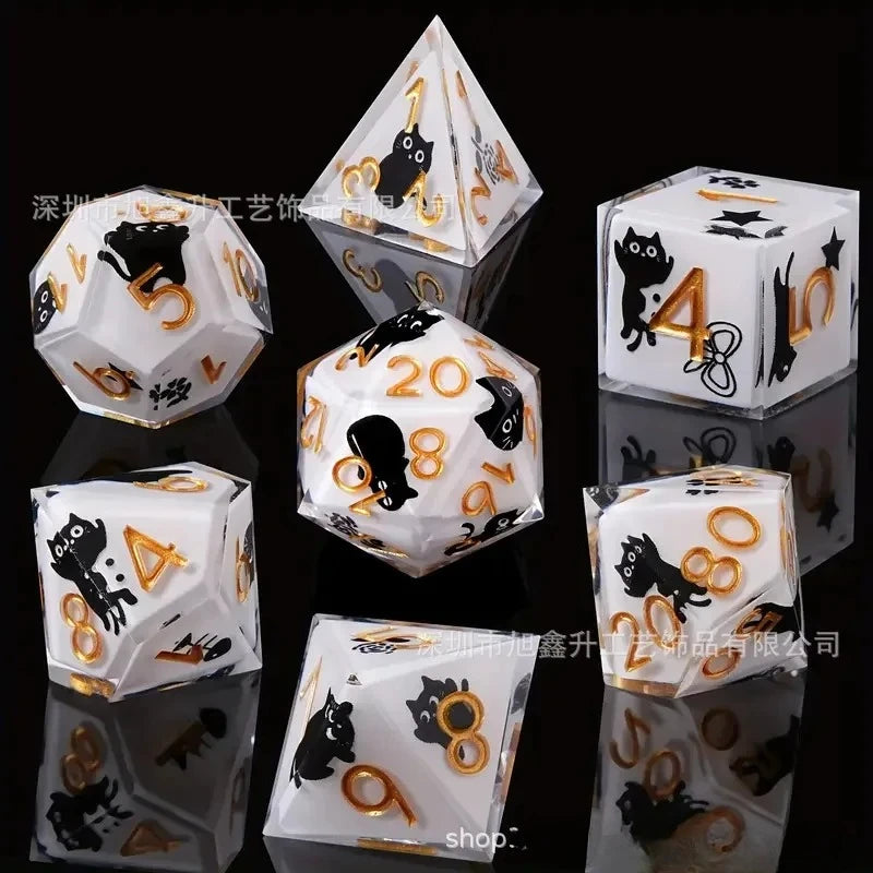 A set of milk white resin dice featuring a black kitten design, displayed on a reflective surface.