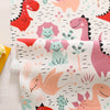A fabric featuring a colorful dinosaur grid print with various pink, orange, and green dinosaurs.