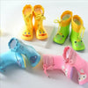 A set of bright yellow rain boots for children, featuring cute animal designs and various colors.