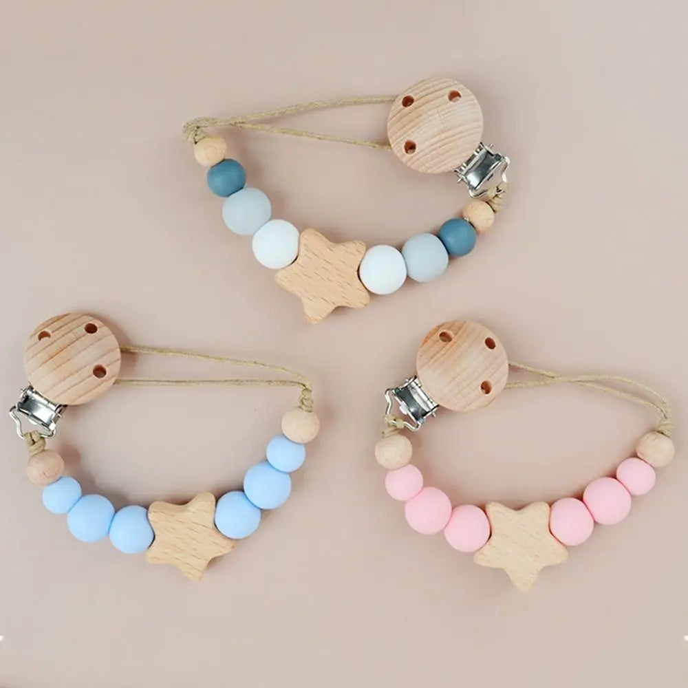 A set of wooden pacifier clips featuring silicone beads in shades of blue, white, and pink.