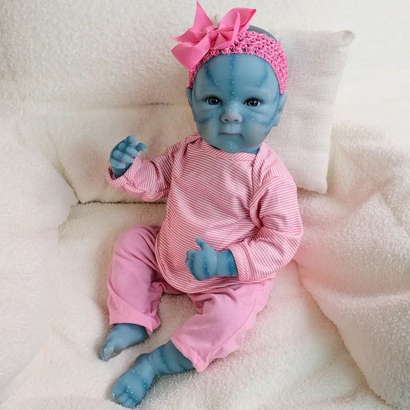 A newborn reborn baby doll with blue skin, pink outfit, and a pink bow accessory lying on white fabric.