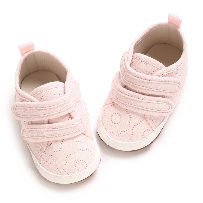 A pair of pink baby first walkers with soft soles and pink fabric details.