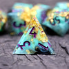 A triangular resin die with a teal and purple marbled pattern and gold accents resting on a dark surface.