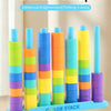 A set of colorful stacking beads in various colors and sizes arranged vertically and scattered on a wooden surface.