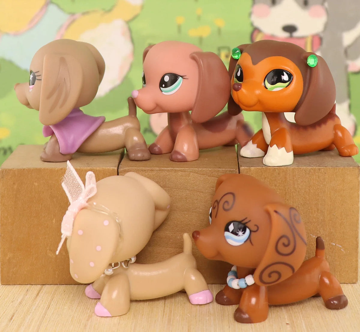 A set of four dachshund bobblehead figurines in various shades of brown and pink sitting on a wooden surface.