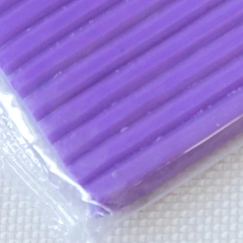 Purple polymer clay modeling clay in a plastic package, showing the ribbed texture.
