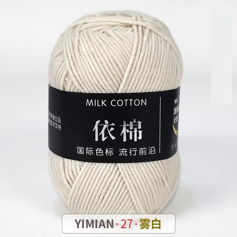 A ball of cream colored milk cotton yarn labeled with Chinese characters and the brand YIMIAN