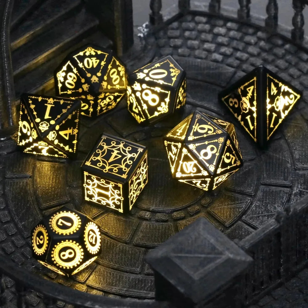 A set of gold-colored LED glow dice and a pyramid die resting on a dark, textured surface.