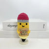 A handwoven crochet pencil ornament featuring a pink knitted cap and yellow body with a heart design.