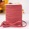 A roll of reddish-pink velvet faux suede braided ribbon for crafting and gift wrapping.