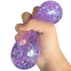 Eine Hand presst einen lila glitzernden Squishy-Dumpling-Sensorikspielzeug.