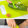 Hands demonstrate using a green plastic play knife set on a yellow cutting board.