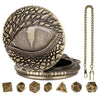 A brass dragon-themed pocket watch dice case with a lid and seven small wooden dice.